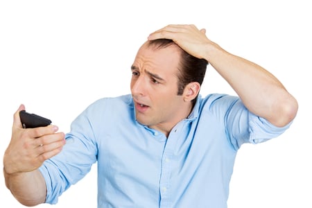 Closeup portrait of shocked man feeling head, surprised he is losing hair, receding hairline or seeing bad news on cellphone, isolated on white background. Negative facial expressions, emotion feeling