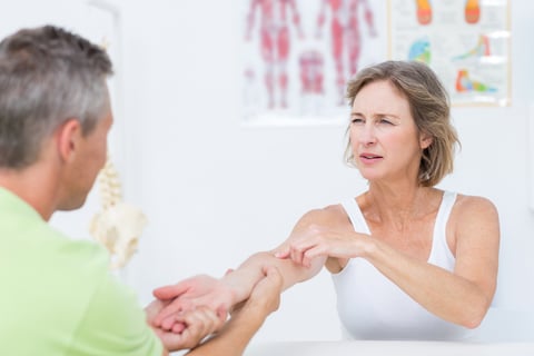 Doctor examining his patients arm in medical office