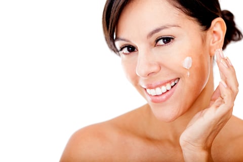 Skincare portrait of a woman putting cream in her face - isolated