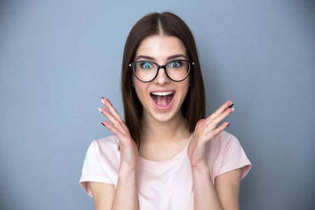 Surprised young woman in glasses over gray background-2
